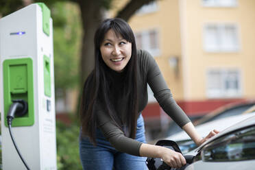 Carsharing, Frau beim Aufladen eines Elektroautos - SGF02632