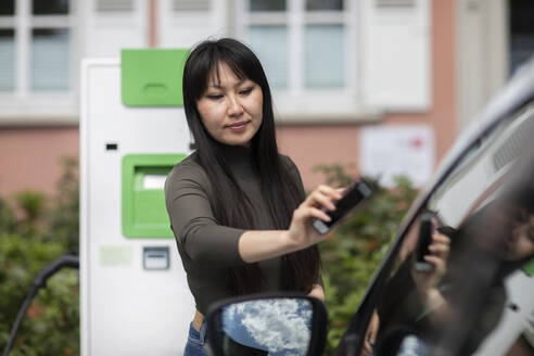 Carsharing, eine Frau mietet ein Elektroauto per Smartphone - SGF02634
