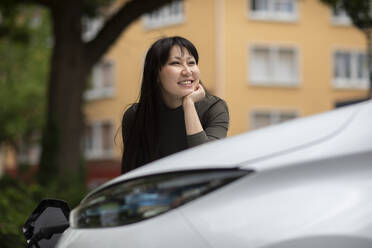 Carsharing, lächelnde Frau beim Aufladen eines Elektroautos - SGF02637