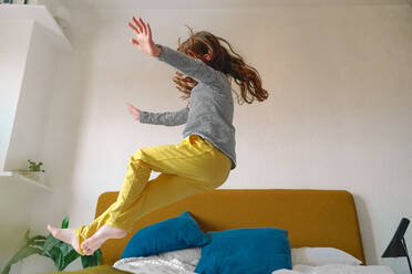 Girl jumping on bed at home - ERRF03733