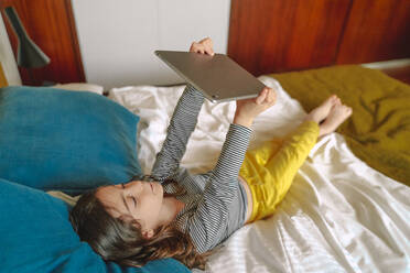 Mädchen nimmt Selfie mit Tablet auf dem Bett liegend zu Hause - ERRF03742