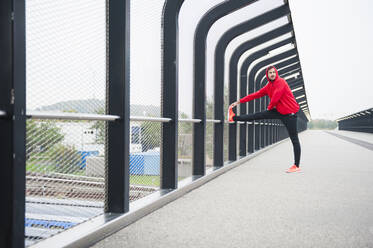 Junger Mann streckt sich auf einer Brücke - DIGF10772