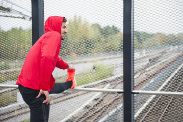 Young man stretching on a railway bridge - DIGF10773