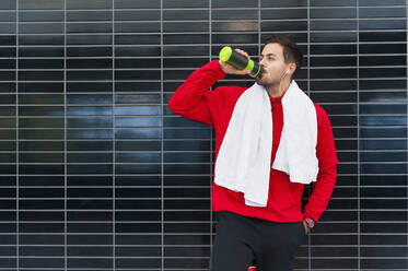 Young man having a break from workout drinking from bottle - DIGF10775