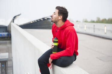 Young man having a break from workout spitting water - DIGF10778