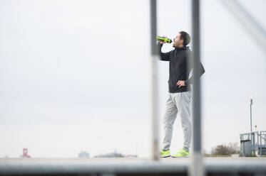 Young man having a break from workout drinking from bottle - DIGF10801