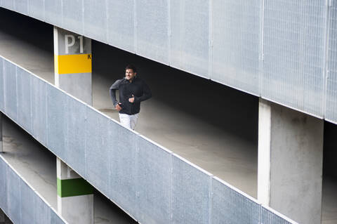 Young man running in a car park stock photo