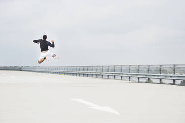 Young man jumping on a parking deck - DIGF10819