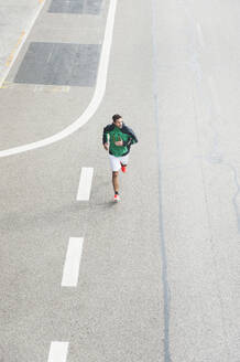 Vogelperspektive eines jungen Mannes, der auf einer Straße läuft - DIGF10822