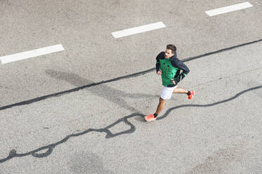 Vogelperspektive eines jungen Mannes, der auf einer Straße läuft - DIGF10823