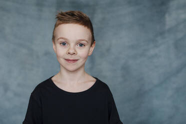 Portrait of smiling cute boy standing at home - OGF00412