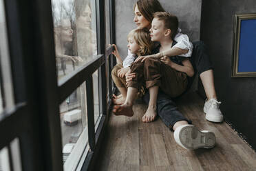 Familie in voller Länge beim Blick durch das Fenster zu Hause - OGF00415