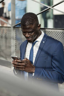 Smiling young businessman looking at cell phone - EGAF00067