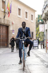 Porträt eines jungen Geschäftsmannes beim Fahrradfahren in der Stadt - EGAF00077