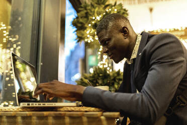 Young businessman working on laptop in a coffee shop - EGAF00091