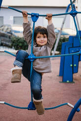 Girl on climbing net in playground - EGAF00092