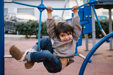 Girl on climbing net in playground - EGAF00093