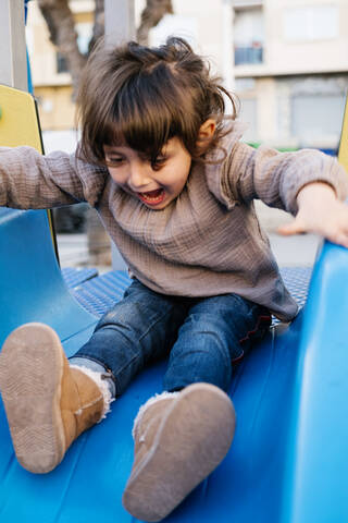 Three-year-old girl playing on a playground swing during the day, lizenzfreies Stockfoto