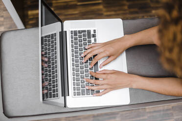 Young woman typing on laptop, view from abaove - DIGF10891