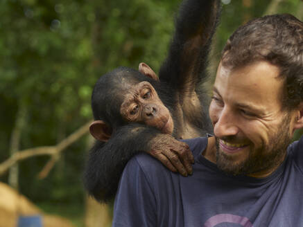 Cameroon, Pongo-Songo, Smiling man with Chimpanzee (Pan troglodytes) on back - VEGF02201