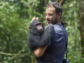 Kamerun, Pongo-Songo, Mann trägt Schimpanse (Pan troglodytes) im Wald - VEGF02204