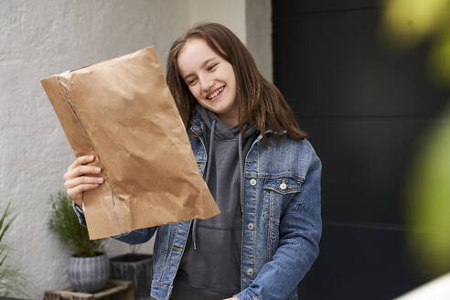 Mädchen steht vor einem Haus und freut sich über ein Paket - AUF00481