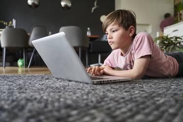 Junge liegt auf dem Boden und arbeitet am Laptop - AUF00485