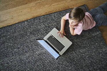 Junge liegt auf dem Boden und arbeitet am Laptop - AUF00491