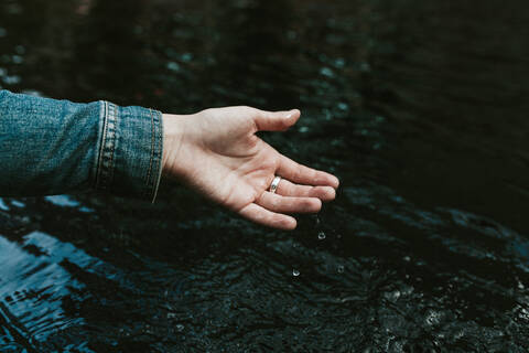 Germany, Young woman wetting hand in pond stock photo