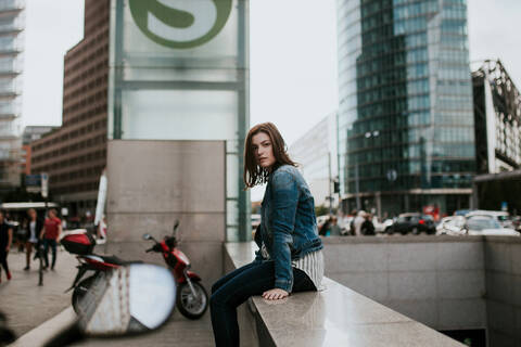 Germany, Berlin, Portrait of young woman sitting on underpass wall stock photo