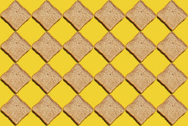 Pattern of slices of wheat bread against yellow background - GEMF03722