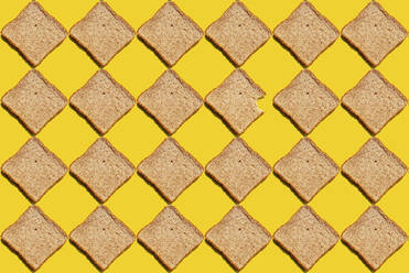 Pattern of slices of wheat bread against yellow background - GEMF03723