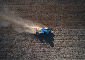 Aerial view of a blue and red tractor ploughing the earth, Rosasco, Lombardy, Italy. - AAEF08361