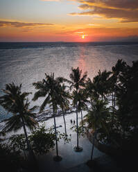 Luftaufnahme eines Paares, das bei Sonnenuntergang in San Juan, Siquijor, Philippinen, am Strand entlang spaziert - AAEF08456