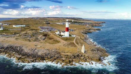 Luftaufnahme des Leuchtturms Portland Bill mit Wellen, die an Felsen krachen, Uk. - AAEF08488