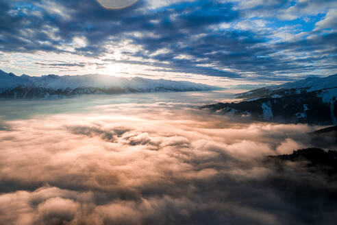 Luftaufnahme eines bewölkten Tals mit Sonnenuntergang in den Alpen bei Piesendorf, Kaprun, Österreich im Winter. - AAEF08549