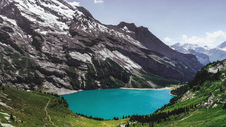 Luftaufnahme des Oeschinensees, Schweiz: Ein kleiner, ruhiger See mit Gletscherwasser und den Schweizer Alpen im Hintergrund. - AAEF08586