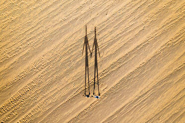 Aerial view of two persons shadows holding hands in desert terrain near Corralejo dunes in Fuerteventura island. - AAEF08637