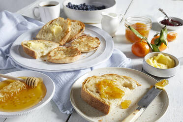 Plates of toast with butter and marmalade, dishes of honey, butter and jams. - CUF55007