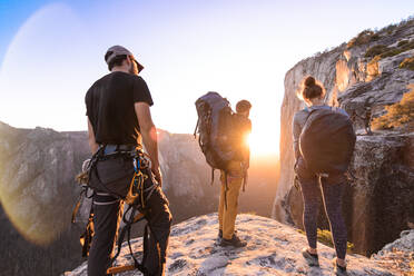 A group of people on a rocky outcrop watching a sunset. - ISF24100