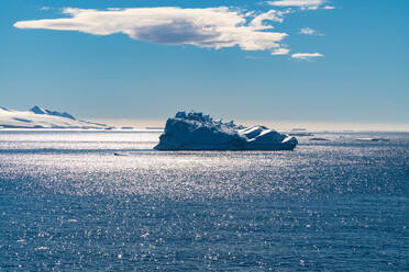 Ein Eisberg, der im südlichen Atlantik unter einem blauen Himmel mit einer Wolke treibt. - ISF24139