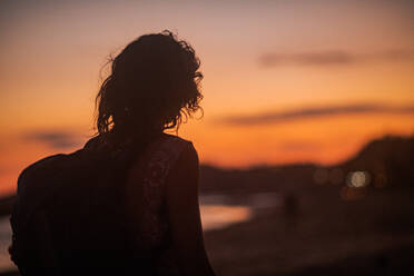 Silhouette eines jungen Menschen mit einem Rucksack am Strand bei Sonnenuntergang. - ISF24171