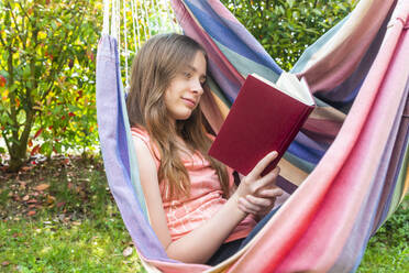 Portrait of girl reading book in hammock - SARF04578