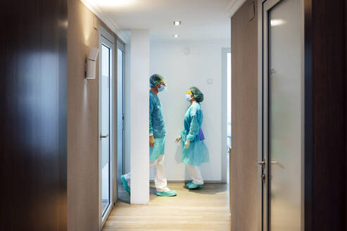 Male and female dentists walking in hallway at clinic - JCMF00726