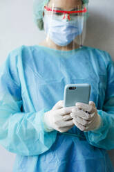 Eine Zahnärztin benutzt ein Mobiltelefon, während sie in der Klinik steht - JCMF00733