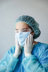 Ältere Ärztin mit Gesichtsschutzmaske und Kittel in einer Klinik - JCMF00735