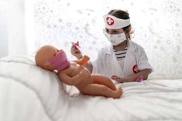 Mädchen im Arztkostüm, das seine Puppe mit einer Maske pflegt - EGAF00095