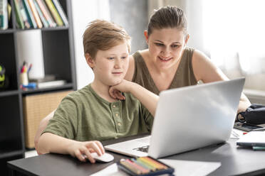 Mutter, die ihren Sohn zu Hause unterrichtet und den Laptop zu Hause benutzt - VPIF02444