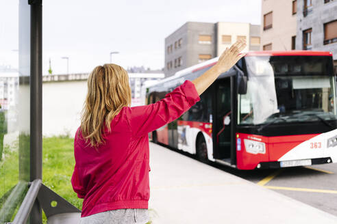 Frau, die den Bus an der Bushaltestelle anhält - DGOF00993