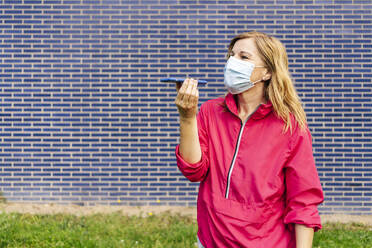 Woman with surgical mask using smartphone - DGOF00997